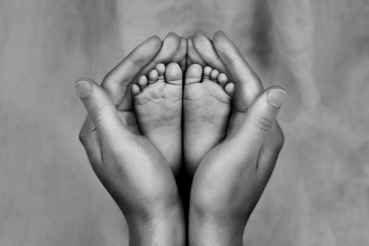 Black and white photo of mother holding baby's feet