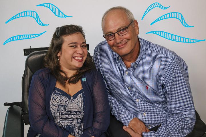 Shelby (25) in chair smiling next to her Dad