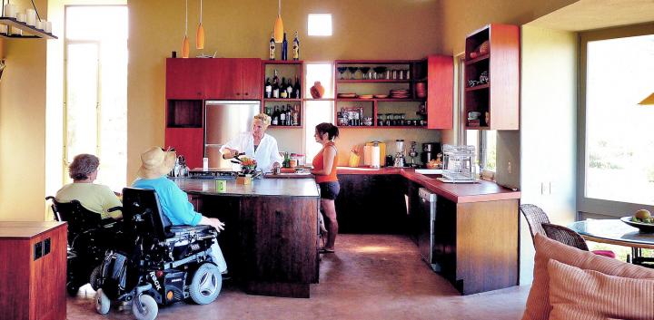 kitchen in house in mexico with two individuals in wheelchairs at the island bench