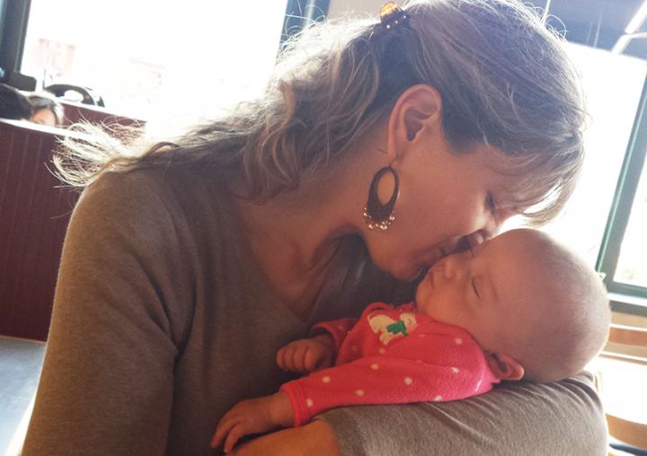 Sarah holding her daughter Taryn and kissing her on the cheek as she's sleeping.