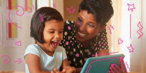 Young girl and woman smiling while looking at a tablet
