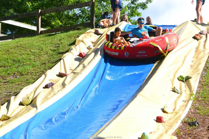 Photo of two young men riding on an inflatable tube down a water slide