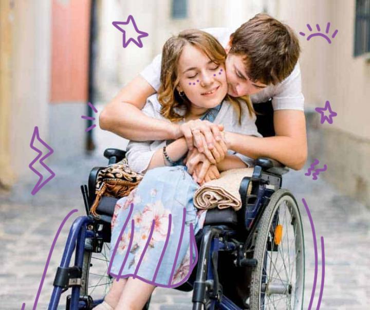 Image of a young woman in a wheelchair being hugged by a young man