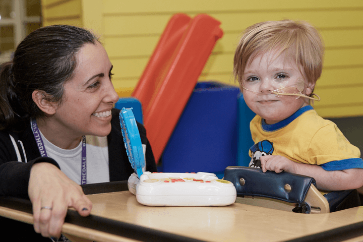 Zach (age 4) smiling in therapy playing a game with PT