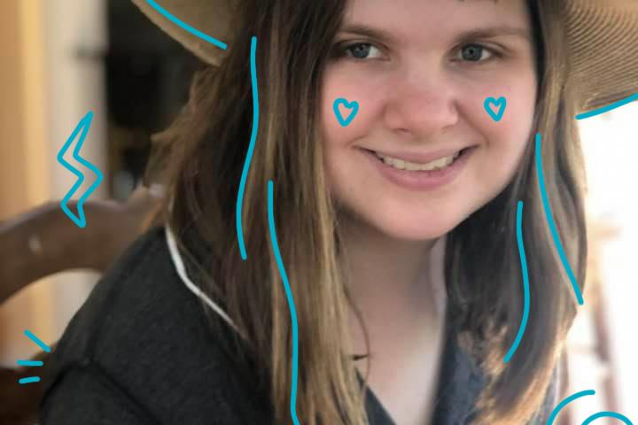 Photo of Lelia Purky wearing a straw har with a yellow flower with blue doodles