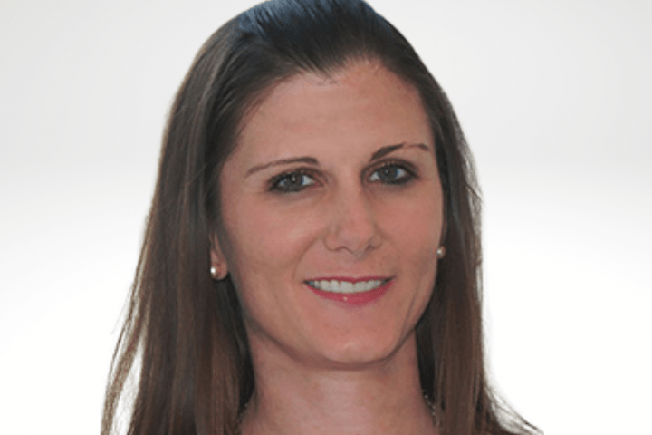 Lorene has long brown hair and is smiling. She is wearing a tan top.