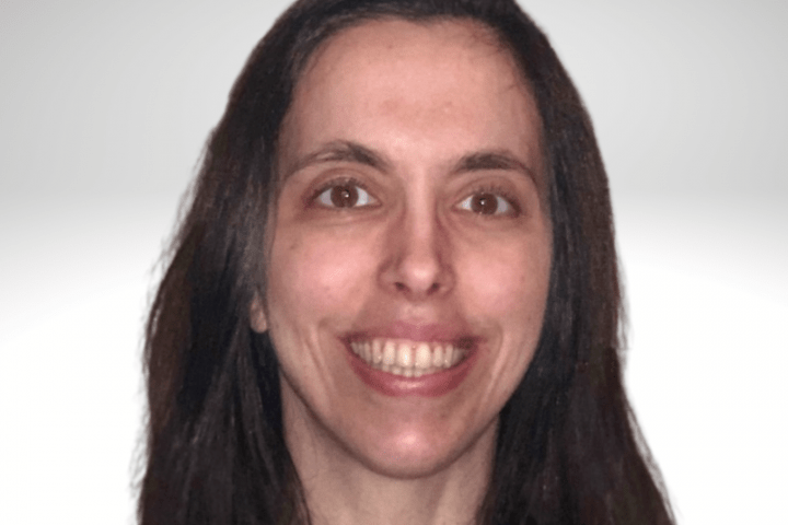 Joycelyn has long brown hair and is smiling. She is wearing a pink shirt.