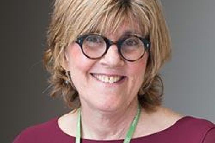 Dr. Golda Mio-Manson wearing a maroon shirt and glasses