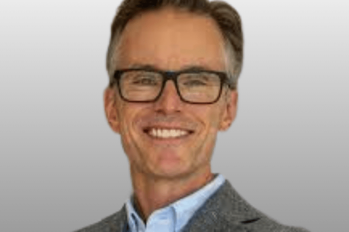 Headshot of Dr. Adam Kirton wearing black framed glasses.