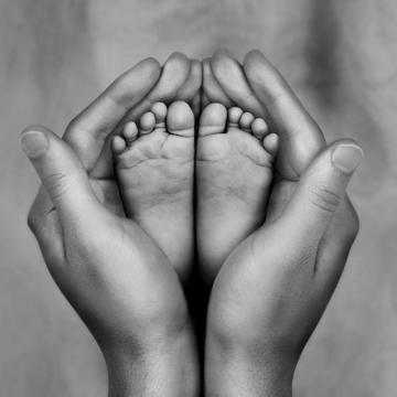 Black and white photo of mother holding baby's feet
