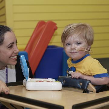 Zach (3 years old) at PT, smiling and playing a game.