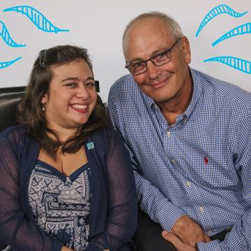 Shelby (25) in chair smiling next to her Dad