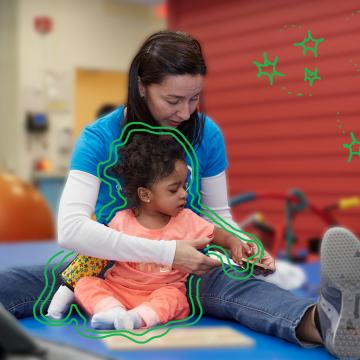 Briana (Age 4) in therapy moving a puzzle piece with her PT