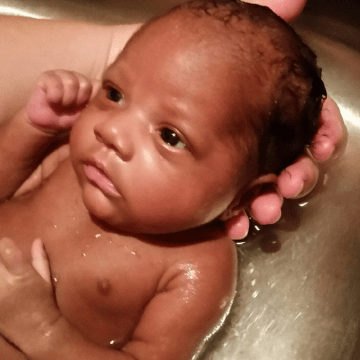 Photo of baby girl being held behind her head while having a bath