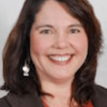 Photo of Mary Ganotti in a red shirt with a black sport coat on a grey background