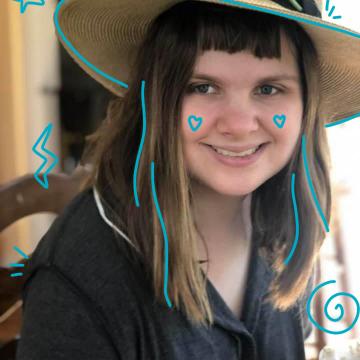 Photo of Lelia Purky wearing a straw har with a yellow flower with blue doodles