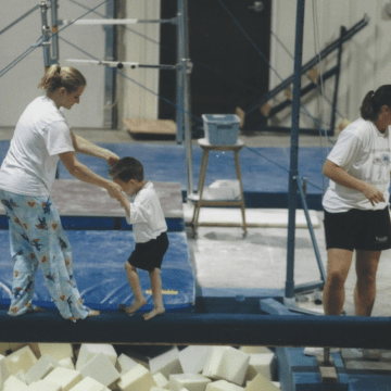 Mason Shrader on the Balance Beam being led by his coach