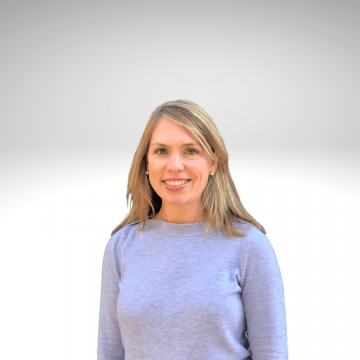 Kristen has long blond hair and is smiling wearing a blue sweater