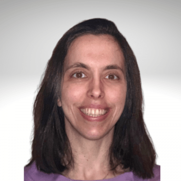 Joycelyn has long brown hair and is smiling. She is wearing a pink shirt.