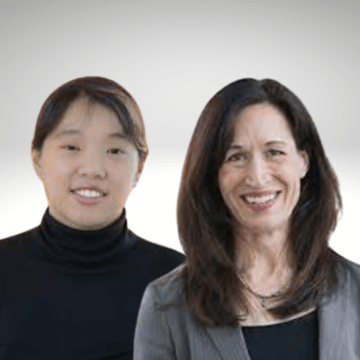 Debbie Song has dark hair pulled back and is wearing a black turtle neck. She is standing next to Marie Ward who has long dark hair and is wearing a grey blazer over a black shirt.