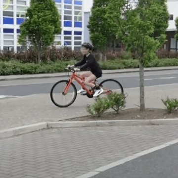 A girl is biking on a road.