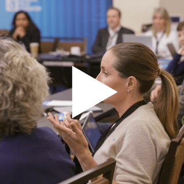 Image of a woman sitting at a conference