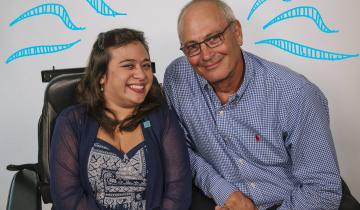 Shelby (25) in chair smiling next to her Dad
