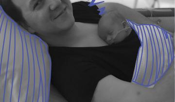 Dad holding newborn son kangaroo style while he sleeps