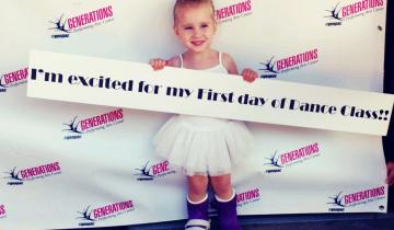 Photo of 4 year old Taryn waering splints on both of her legs holding a sign at her dance recital