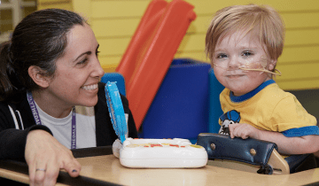 Zach (age 4) smiling in therapy playing a game with PT