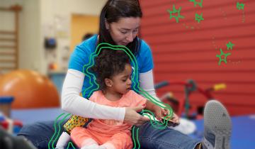 Briana (Age 4) in therapy moving a puzzle piece with her PT
