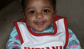 photo of 9 month old baby sitting and smiling at camera