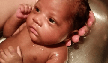 Photo of baby girl being held behind her head while having a bath