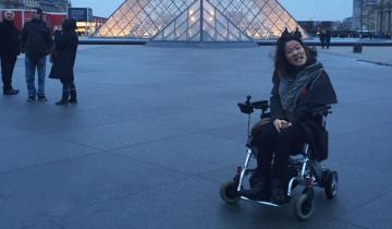 "A Trip Down the Memory Lane of Traveling: Part One" written in text below image of writer, Sarah Kim, in front of the Louvre Pyramid in Paris, France
