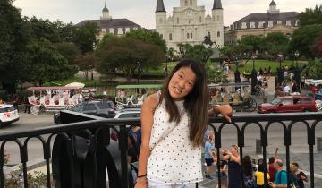 "A Trip Down the Memory Lane of Traveling: Part Two" in text above image of writer, Sarah Kim, in front of Jackson Square in New Orlean's French Quarter