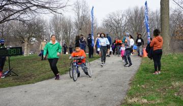 Woman in green shirt and black pants running next to a young boy in an orange shirt in a frame runner