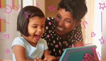 Young girl and woman smiling while looking at a tablet
