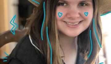 Photo of Lelia Purky wearing a straw har with a yellow flower with blue doodles