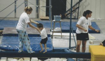 Mason Shrader on the Balance Beam being led by his coach