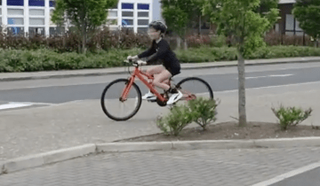 A girl is biking on a road.