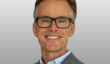 Headshot of Dr. Adam Kirton wearing black framed glasses.