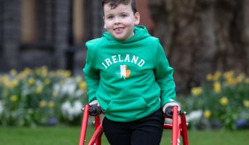 Image of a young boy with dark hair and wearing a green sweatshirt that says Ireland on it..