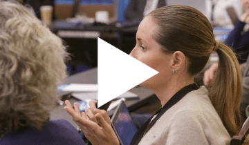 Image of a woman sitting at a conference