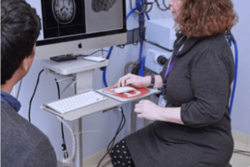 Researcher Kathleen Friel sitting in front of a computer reviewing a black and white image of the brain 