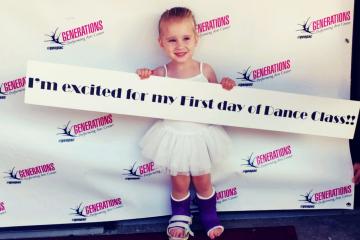 Photo of 4 year old Taryn waering splints on both of her legs holding a sign at her dance recital