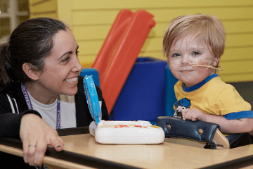 Zach (age 4) smiling in therapy playing a game with PT