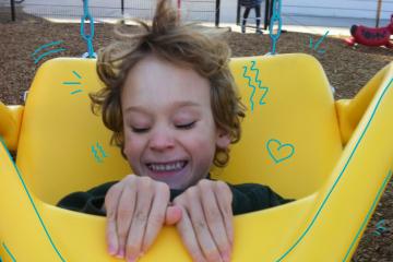 Smiling boy in yellow adaptive swing
