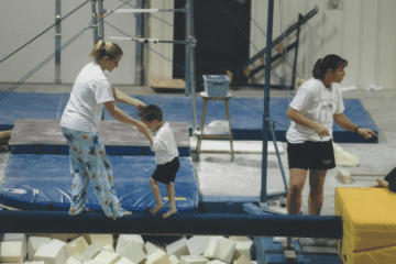 Mason Shrader on the Balance Beam being led by his coach
