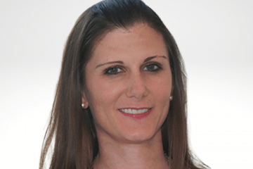 Lorene has long brown hair and is smiling. She is wearing a tan top.