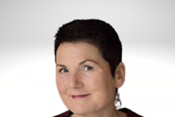 Lily has short pixie like black hair and is smiling for the camera. She is wearing a maroon top. 